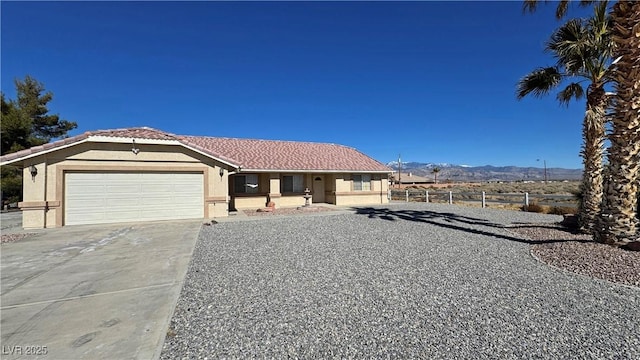 view of front of property featuring driveway, a garage, a tile roof, fence, and stucco siding