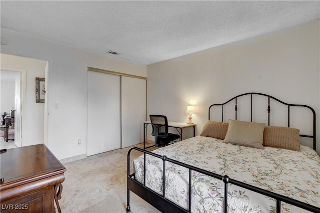 bedroom with a textured ceiling, a closet, and visible vents