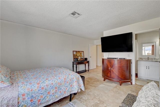 bedroom featuring a textured ceiling, visible vents, and a sink