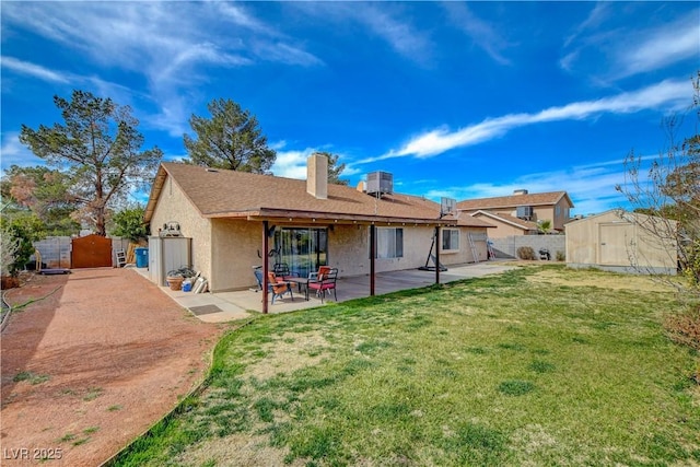 back of property featuring a lawn, a patio area, fence, a shed, and an outdoor structure