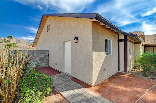 view of side of home with fence, a patio, and stucco siding