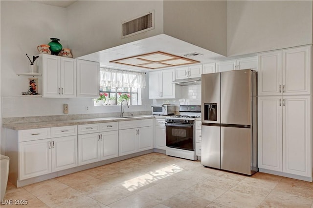 kitchen featuring under cabinet range hood, a sink, visible vents, white range with gas cooktop, and stainless steel refrigerator with ice dispenser