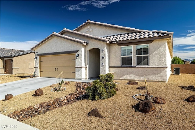 mediterranean / spanish house featuring cooling unit, a garage, concrete driveway, a tiled roof, and stucco siding