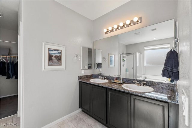 bathroom with double vanity, a stall shower, a sink, and tile patterned floors