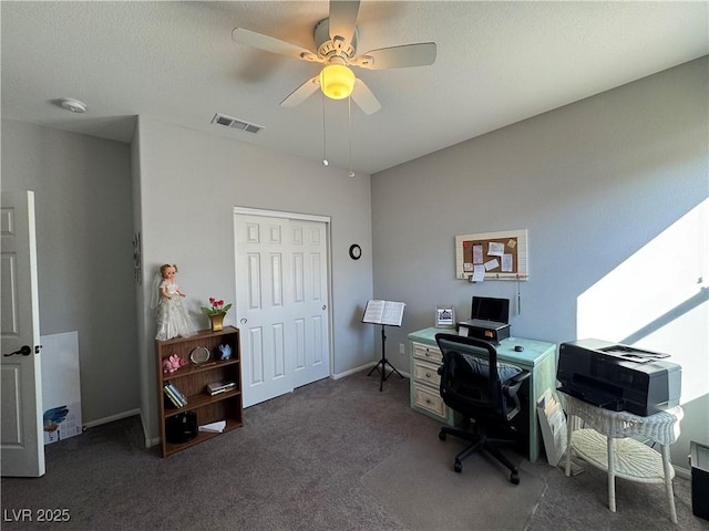 carpeted office featuring baseboards, a textured ceiling, visible vents, and a ceiling fan