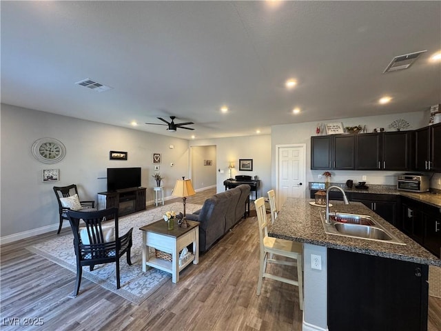 kitchen featuring visible vents, open floor plan, a sink, and wood finished floors