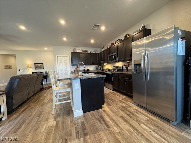 kitchen with open floor plan, stainless steel appliances, a sink, and light wood-style floors