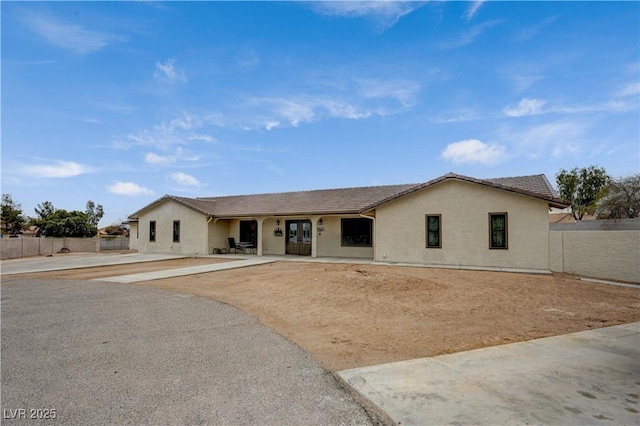 single story home featuring french doors, fence, and stucco siding