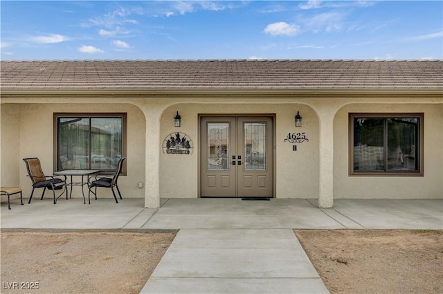 view of exterior entry with french doors and stucco siding