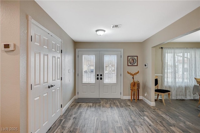 foyer featuring baseboards, visible vents, wood finished floors, and french doors