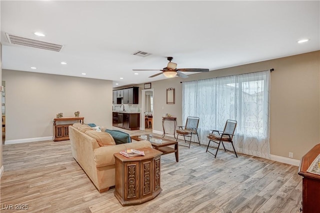 living area with light wood-style floors, visible vents, and baseboards