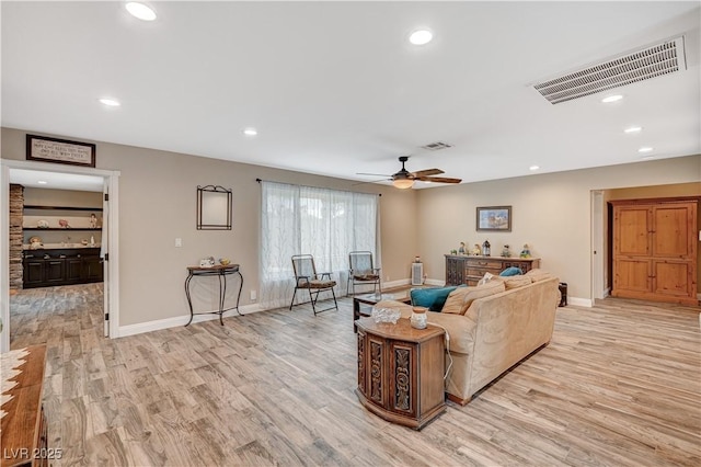 living area with light wood-style flooring, visible vents, baseboards, and recessed lighting