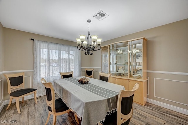 dining space featuring light wood finished floors, visible vents, and a notable chandelier