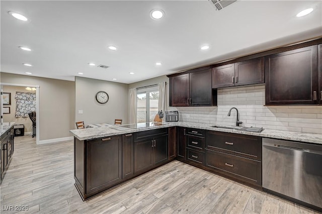 kitchen with a peninsula, stainless steel dishwasher, dark brown cabinets, light wood-style floors, and a sink