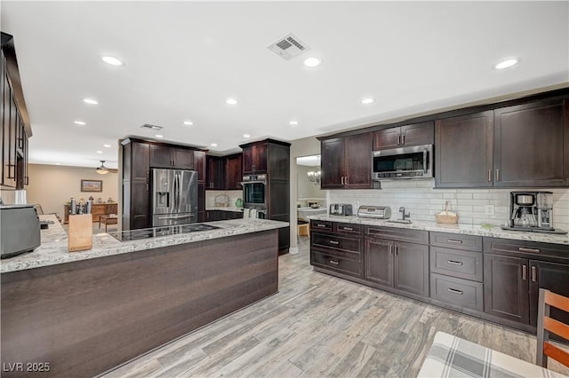 kitchen with dark brown cabinetry, tasteful backsplash, visible vents, light stone countertops, and stainless steel appliances