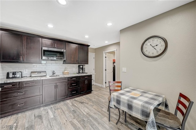 kitchen featuring dark brown cabinetry, stainless steel microwave, light wood-type flooring, backsplash, and recessed lighting