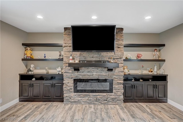 bar featuring a stone fireplace, recessed lighting, wood finished floors, and baseboards