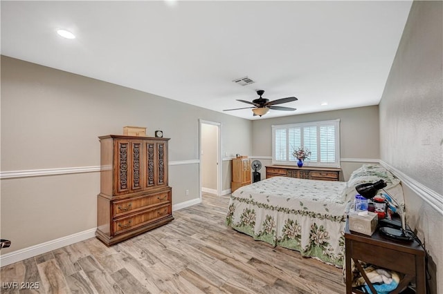 bedroom with a ceiling fan, visible vents, baseboards, and wood finished floors