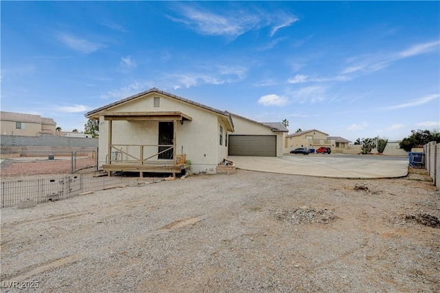 view of front of property featuring concrete driveway, an attached garage, fence, and stucco siding