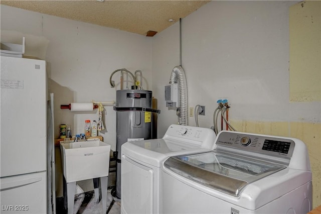 washroom featuring laundry area, water heater, a textured ceiling, and washing machine and clothes dryer