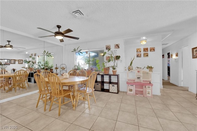 dining room with a ceiling fan, visible vents, light tile patterned flooring, and a textured ceiling