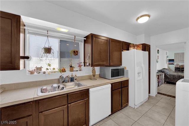 kitchen featuring white appliances, a sink, tile countertops, and light tile patterned floors