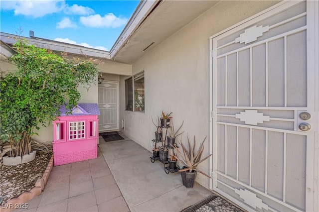 view of exterior entry featuring a patio and stucco siding