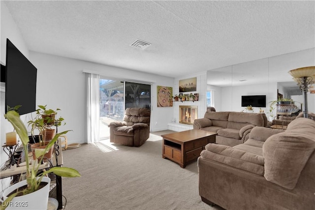 living room with a large fireplace, visible vents, a textured ceiling, and light colored carpet