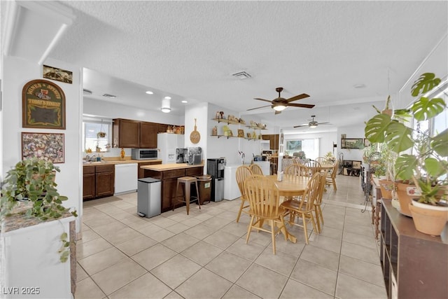 dining space featuring a textured ceiling, light tile patterned floors, and visible vents