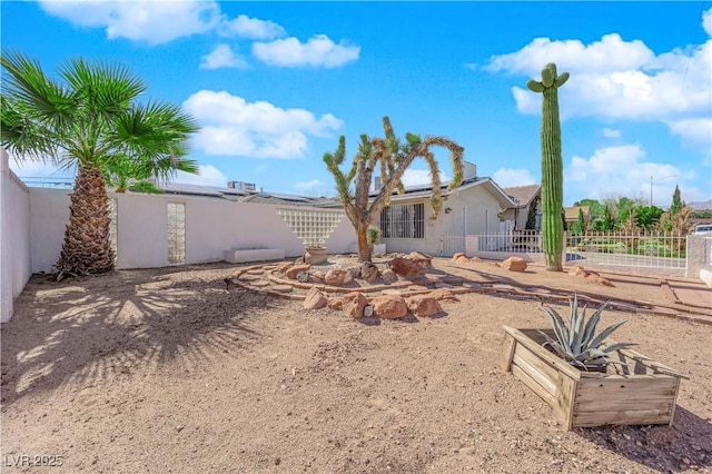 rear view of property featuring solar panels, a fenced backyard, and stucco siding