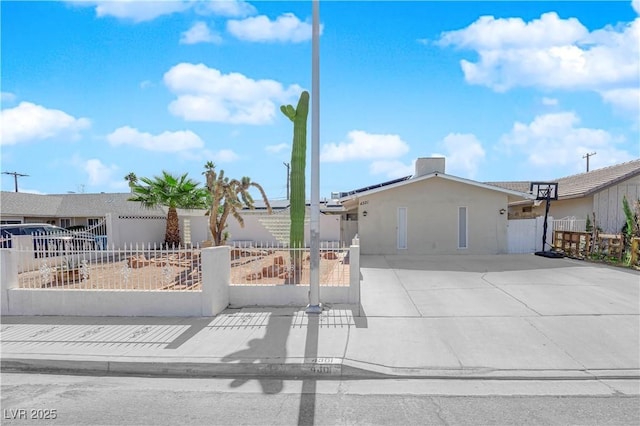 view of front facade with a fenced front yard, solar panels, and stucco siding