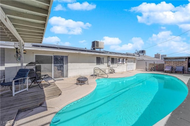 view of swimming pool featuring an outdoor fire pit, central AC unit, a fenced in pool, and a patio