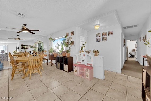 dining area with a ceiling fan, visible vents, a textured ceiling, and light tile patterned flooring