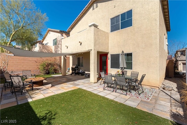 rear view of house with an outdoor fire pit, fence, a patio, and stucco siding