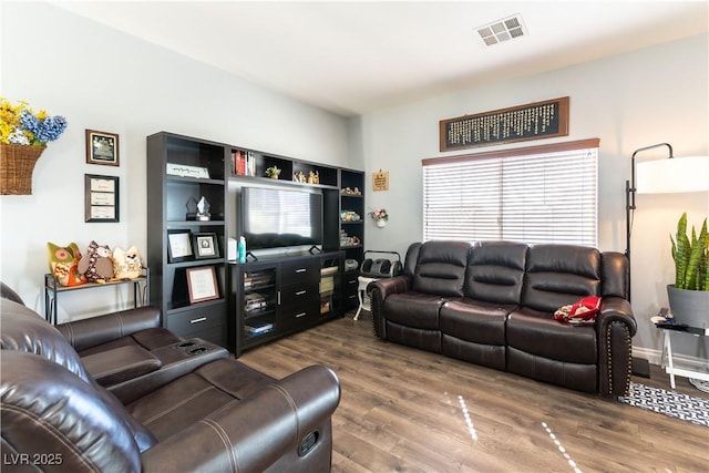 living area with baseboards, visible vents, and wood finished floors