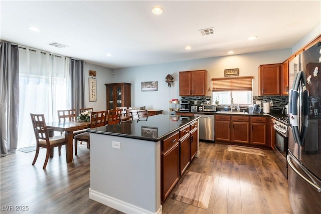 kitchen featuring a center island, dark countertops, visible vents, appliances with stainless steel finishes, and a sink