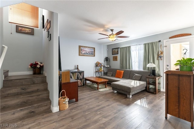 living area featuring ceiling fan, stairway, wood finished floors, and baseboards