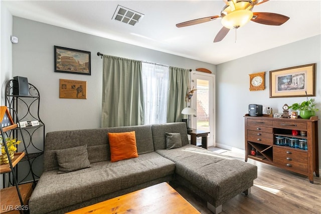 living room with a ceiling fan, visible vents, and wood finished floors