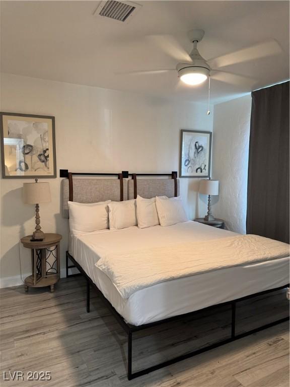 bedroom with wood finished floors, visible vents, and a ceiling fan