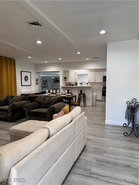 living area with light wood-type flooring, recessed lighting, visible vents, and baseboards