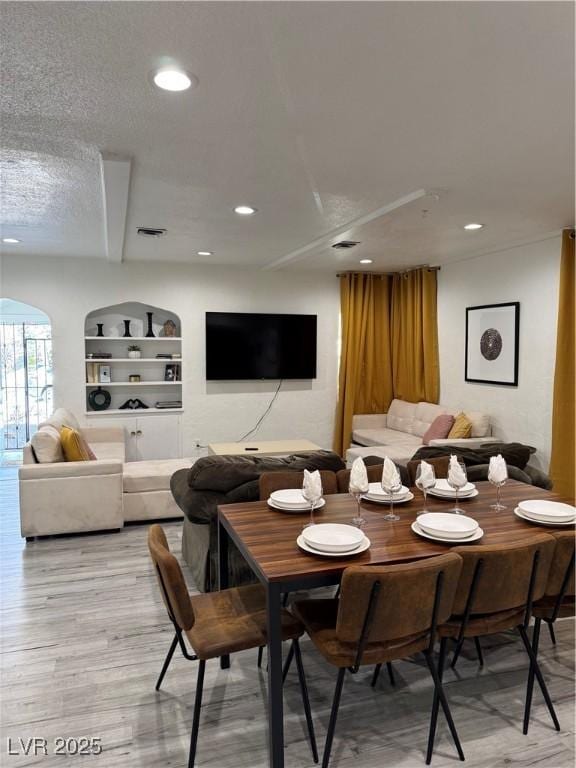 dining room with light wood-type flooring, visible vents, a textured ceiling, and recessed lighting