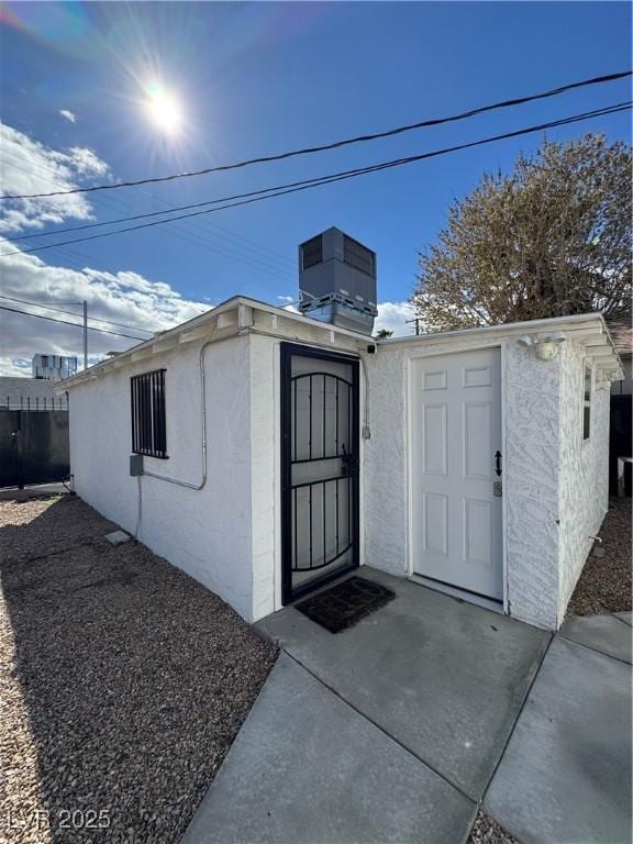 view of outdoor structure with central air condition unit and fence