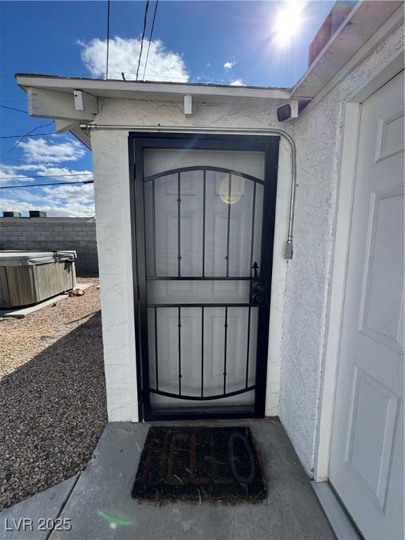 doorway to property featuring fence and stucco siding