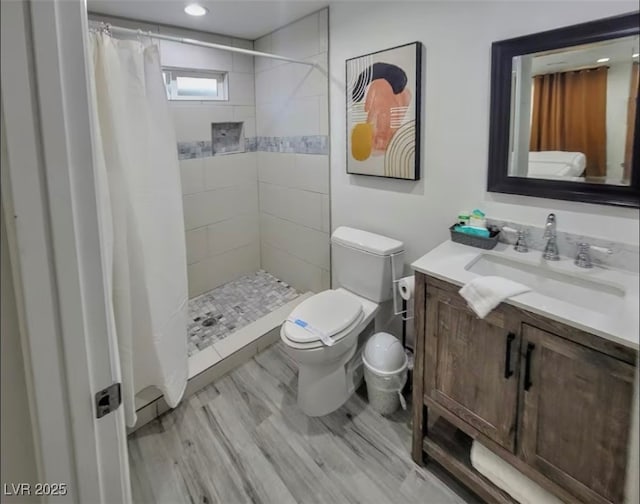 full bathroom featuring recessed lighting, a tile shower, wood finished floors, toilet, and vanity