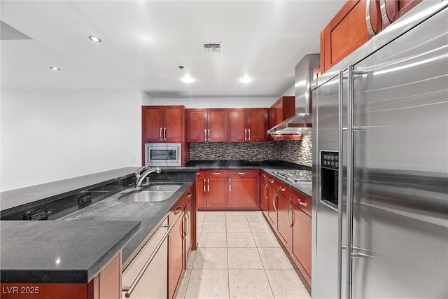 kitchen with light tile patterned floors, a sink, appliances with stainless steel finishes, decorative backsplash, and wall chimney exhaust hood