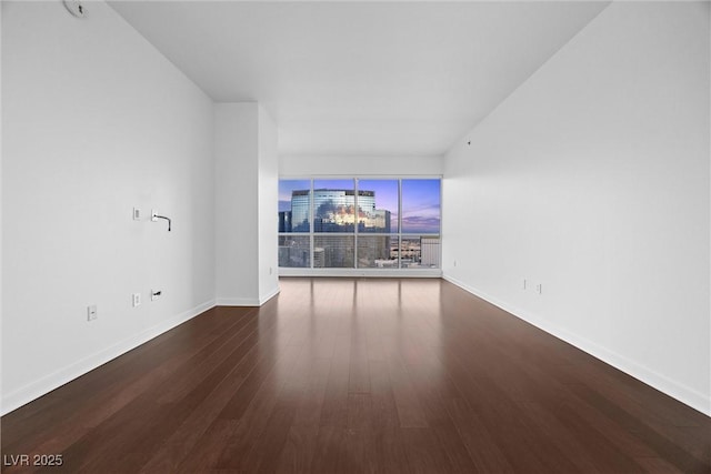 unfurnished living room featuring dark wood finished floors and baseboards