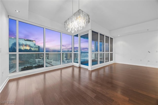 unfurnished room featuring baseboards, recessed lighting, wood finished floors, and a notable chandelier