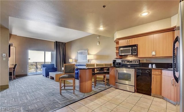 kitchen featuring dark countertops, a kitchen breakfast bar, open floor plan, a peninsula, and stainless steel appliances