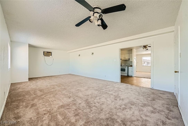 carpeted empty room with a wall unit AC, a textured ceiling, and a ceiling fan