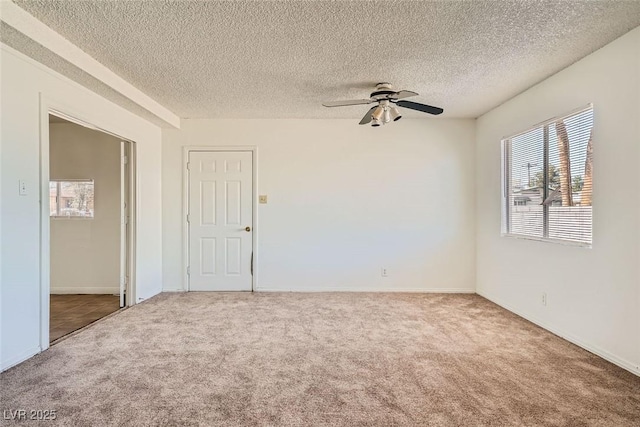 unfurnished room featuring carpet, ceiling fan, a textured ceiling, and baseboards